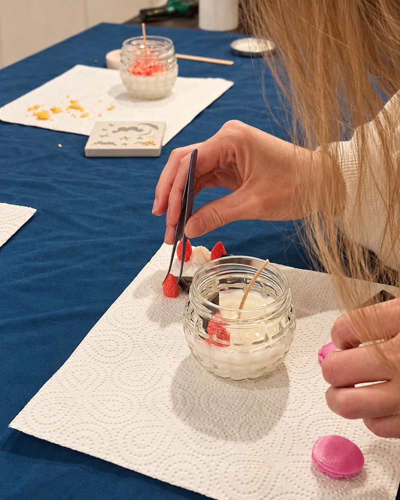 Participante assemblant les décors de sa bougie personnalisée à l’aide d’une pince.