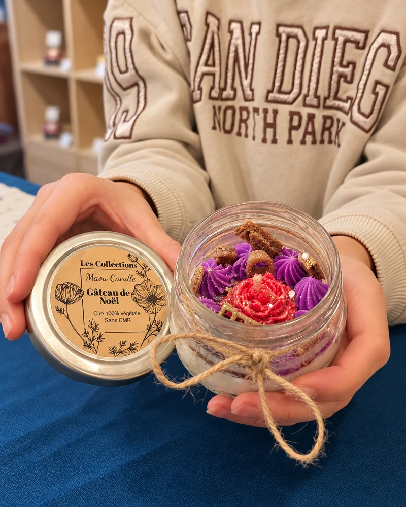 Bougie personnalisée ornée de décors en cire violets et rouges, présentée dans les mains d’une participante.