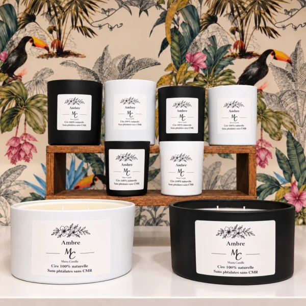 Bougies parfumées Ambre Maou Candle en pots noirs et blancs, disposées devant un décor floral coloré.